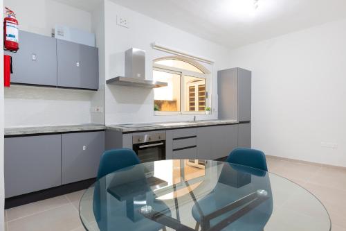a kitchen with a glass table and blue chairs at Xmajjar in Sliema