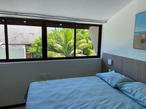 um quarto com uma cama e uma grande janela em Muro alto Bangalô beach class ecolife em Porto de Galinhas