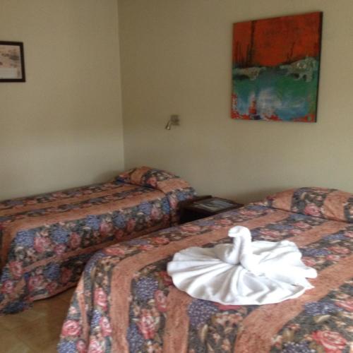 a hotel room with two beds with a towel on them at Hotel Wagelia Turrialba in Turrialba