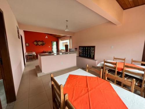 a dining room and kitchen with an orange table and chairs at Pousada dos Contos de Carrancas in Carrancas