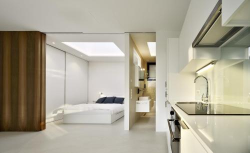a white kitchen with a bed in a bedroom at Mirror Houses in Bolzano