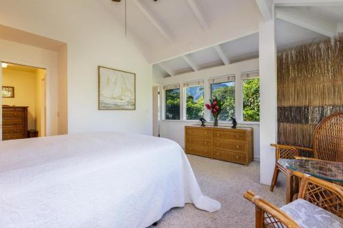 a bedroom with a large white bed and windows at Hanalei Palms home in Hanalei