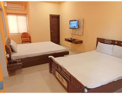 um quarto com duas camas e uma televisão na parede em Hotel Diamond Vihar, Rajgir em Rajgir
