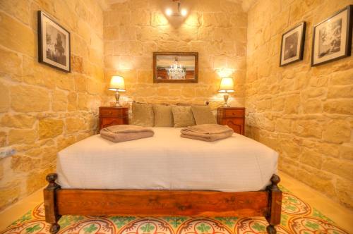 ein Schlafzimmer mit einem großen Bett in einer Steinmauer in der Unterkunft Casa Bartolo A Hidden Gem - Spacious Village Home EBAR1-1 in Lija