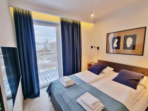 - une chambre avec 2 lits et une grande fenêtre dans l'établissement Apartament Bliżej Morza w Gąskach - 365PAM, à Gąski