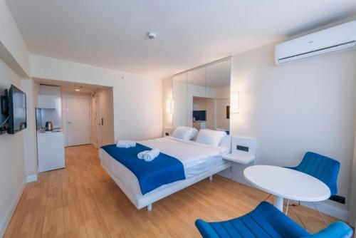 a bedroom with a bed and two blue chairs at Orbi City Sea View in Batumi
