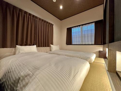 1 dormitorio con 2 camas y ventana en 橋旅西雅院 Kyoryosaiga Inn, en Kioto