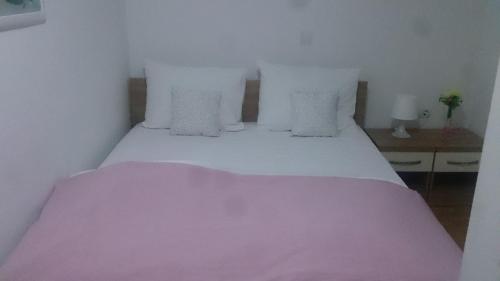 a bed with white sheets and pillows in a room at Lugarnica in Zagreb