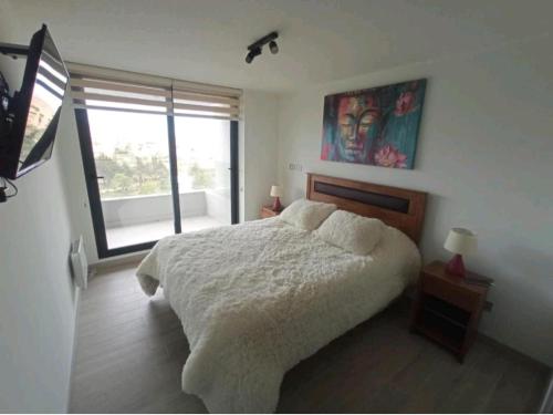 una camera con un letto e una grande finestra di Hermoso Departamento dunas de concon a Concón