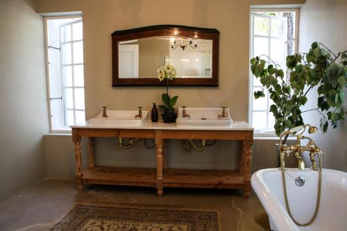ein Badezimmer mit zwei Waschbecken, einer Badewanne und einem Spiegel in der Unterkunft San Gabriel Homestead in Somerset West