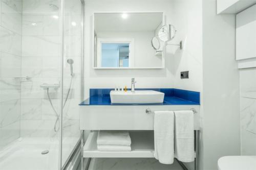 uma casa de banho branca com um lavatório e um chuveiro em Orbi City Sea View em Batumi