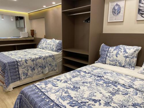 1 dormitorio con 2 camas con sábanas azules y blancas en Pipa's Bay - Flats para temporada, en Pipa