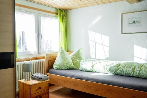 ein Schlafzimmer mit einem Bett mit grünen Kissen und einem Fenster in der Unterkunft Gästehaus Aemisegg in Sankt Peterzell