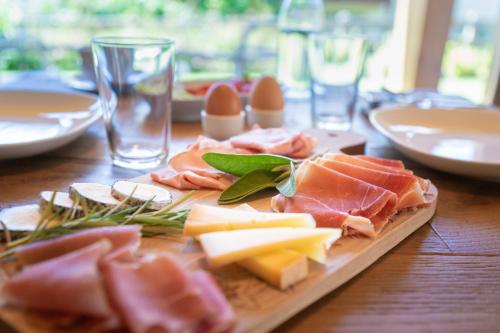 een houten tafel met kaas en vlees op een snijplank bij 21Barra5 Guest House in Aosta