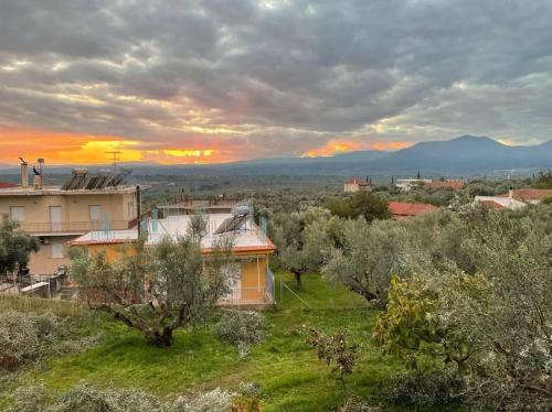 uma casa num campo com um pôr-do-sol ao fundo em Beautiful & cosy 5-Bedroom Villa - Peloponnese em Pídhima