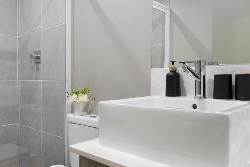 a white bathroom with a sink and a mirror at Urban Oasis Apartments at The Bolton in Johannesburg