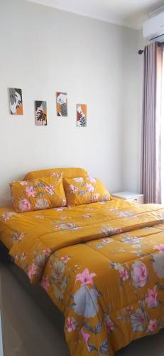 a bed with a yellow blanket with flowers on it at Villa Kayana EE6 - 3 Bedrooms in Batu