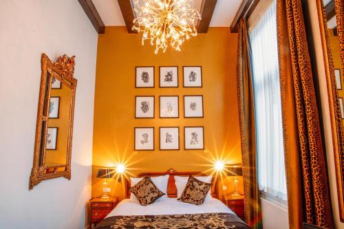 1 dormitorio con cama, espejo y lámpara de araña en Ambassade Hotel, en Ámsterdam