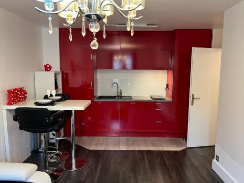 una cucina con armadi rossi e bancone bianco di Appt 4P, parking, Disney direct, Vallée Village a Serris