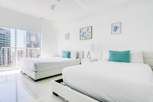 una camera da letto bianca con due letti e un divano di Penthouse with Ocean and City Views in Lux Miami Brickell Sleeps 4 a Miami