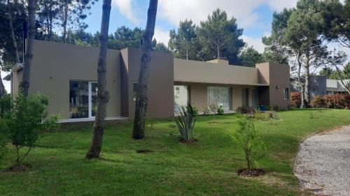 una casa con árboles delante de ella en La Herradura en Pinamar