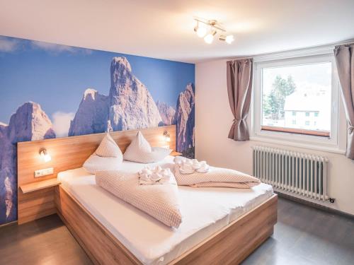 ein Schlafzimmer mit einem Bett mit einem Wandbild der Berge in der Unterkunft Haus Kristall in Tannheim