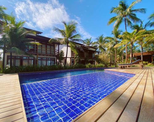 uma piscina em frente a uma casa com palmeiras em 105 Condo Dreamland Apts BeachFront - Taipu de Fora em Maraú