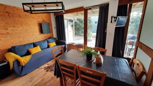 un salon avec une table et un canapé bleu dans l'établissement Chaleureux appartement aux pieds des pistes, à Chamrousse