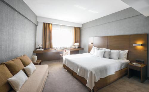 a hotel room with a bed and a couch at Anatolia Hotel in Thessaloniki