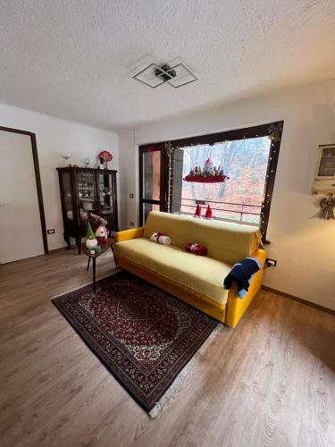 Gin Sole Apartment في Artogne: غرفة معيشة مع أريكة صفراء أمام نافذة