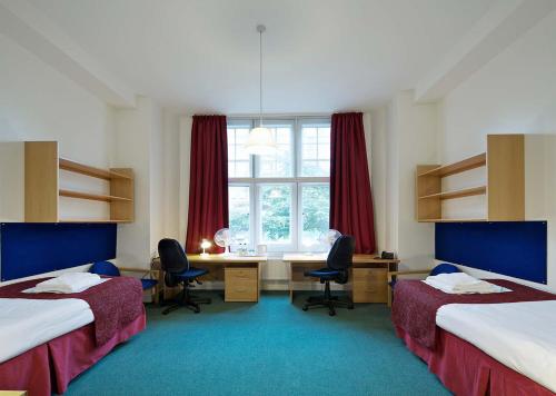 a room with two beds and a desk and a window at Beit Hall in London