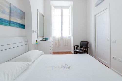 um quarto branco com uma cama e uma cadeira em HC Home Claudia em Cagliari