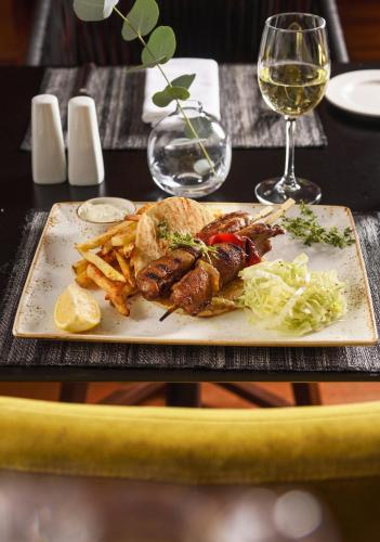 a plate of food with french fries and a glass of wine at Anatolia Hotel in Thessaloniki