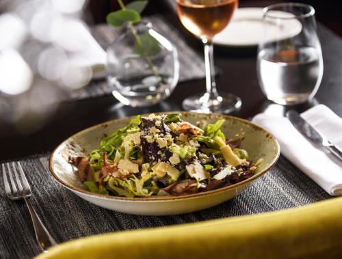 a bowl of salad on a table with wine glasses at Anatolia Hotel in Thessaloniki