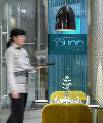 a woman standing in front of a table with a tray at Anatolia Hotel in Thessaloniki