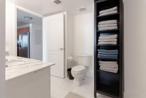 a bathroom with a toilet and a shelf with towels at Sunshine Ocean and City Views 1 BR Paradise with Parking in Miami