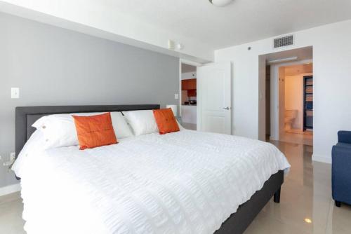 a bedroom with a large white bed with orange pillows at Sunshine Ocean and City Views 1 BR Paradise with Parking in Miami