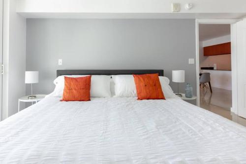 a large white bed with orange pillows on it at Sunshine Ocean and City Views 1 BR Paradise with Parking in Miami