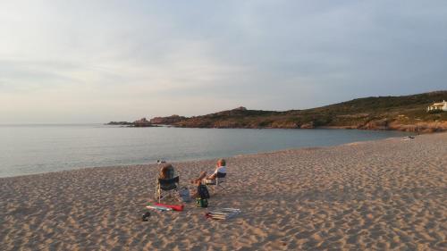 three people sitting on a beach near the water at La Vignaredda - Residenza di Charme in Aggius