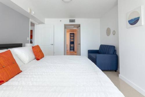 a bedroom with a large white bed and a blue chair at Sunshine Ocean and City Views 1 BR Paradise with Parking in Miami