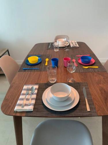 a wooden table with plates and glasses on it at Sunshine Ocean and City Views 1 BR Paradise with Parking in Miami