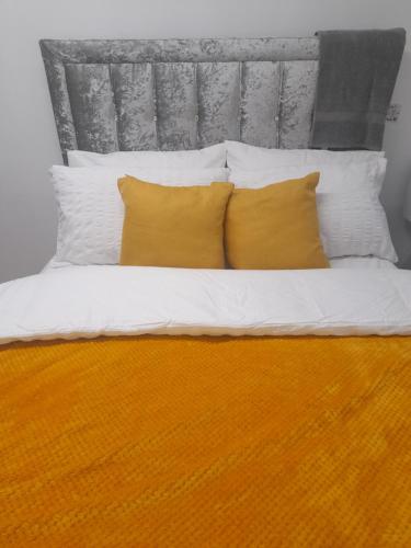 a bed with two yellow pillows and a headboard at 1 bed studio in Luton