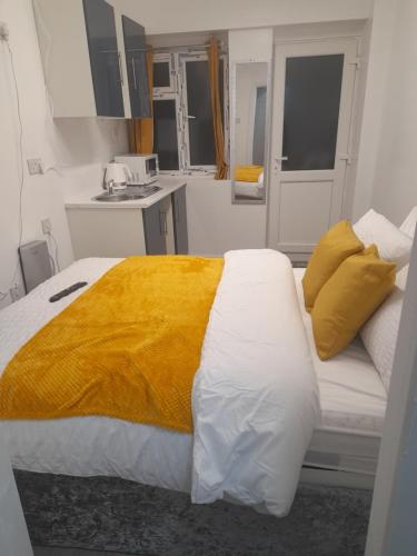 a bedroom with a large bed with a yellow blanket at 1 bed studio in Luton
