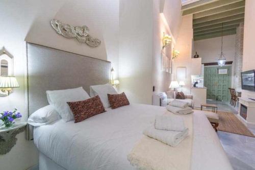 a bedroom with a large white bed and a living room at Judería de Sevilla I Luxury Apartments in Seville