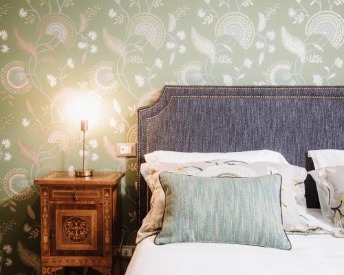 a bedroom with a bed with a blue pillow and floral wallpaper at Ca'Lisel in Valdobbiadene