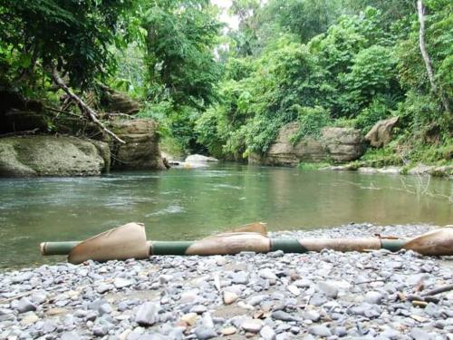 duas pessoas deitadas nas rochas perto de um rio em Tour & Travel Guide em Bukit Lawang