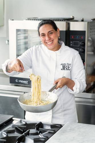 a woman in a kitchen stirring a bowl of food at Hotel Signum in Malfa