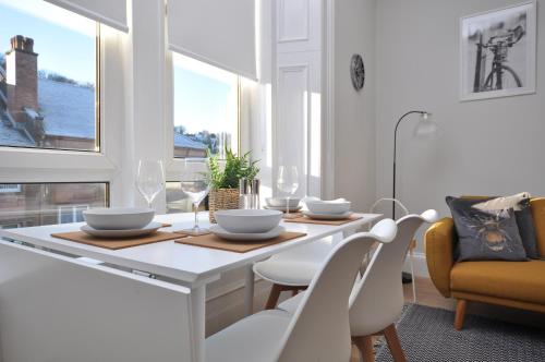 a white dining room with a table and chairs at The Warren Apartment in Greenock