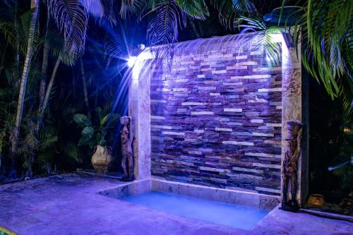 a stone wall with a shower in a backyard at night at Casa Linda beautiful Villa in Sosúa