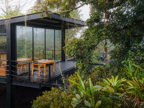 une maison en verre avec une table et des chaises sur la terrasse dans l'établissement Bio Habitat hotel, à Armenia